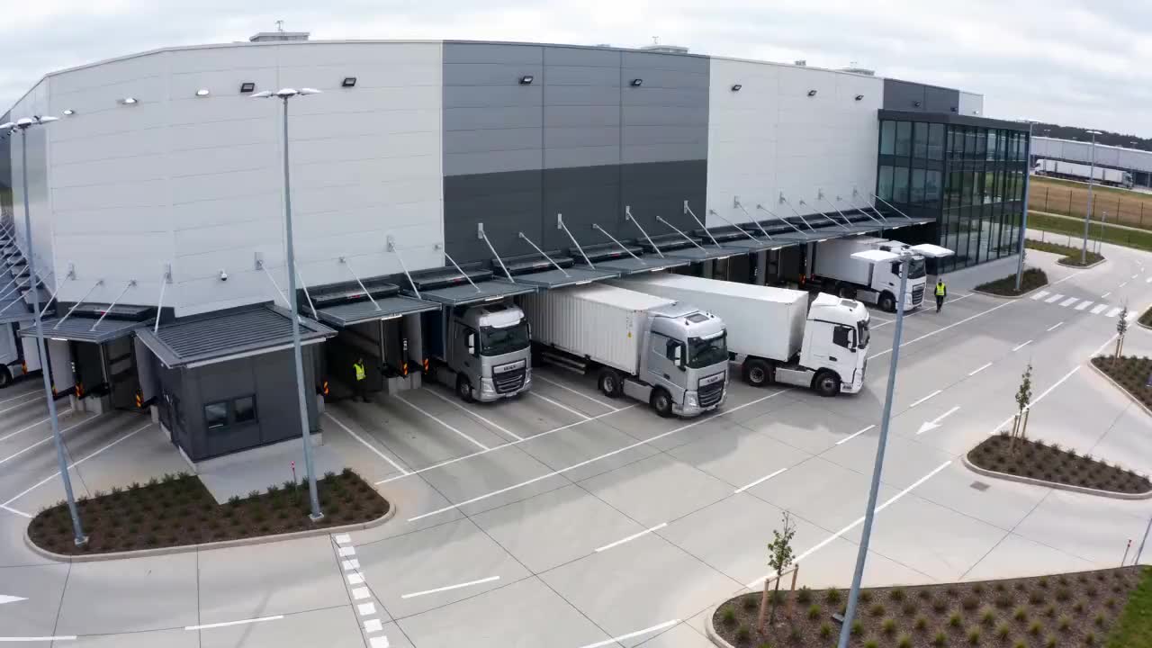 Yard camera view: lorries stand at the loading docks while another manoeuvres into a bay.